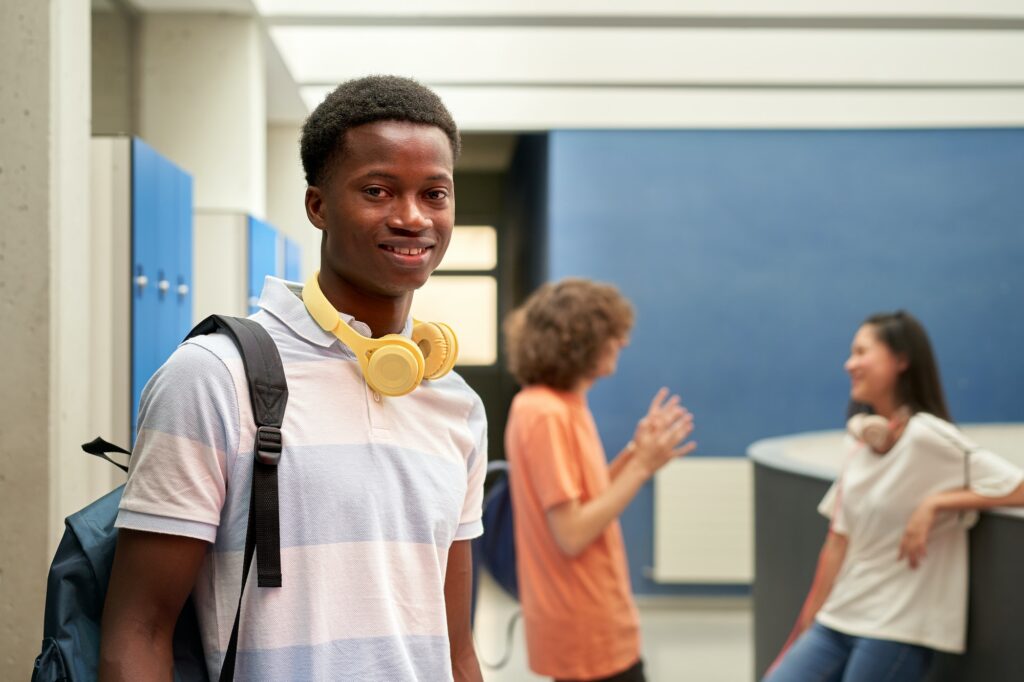 Portrait of an African American student looking at the camera in the school hallway.