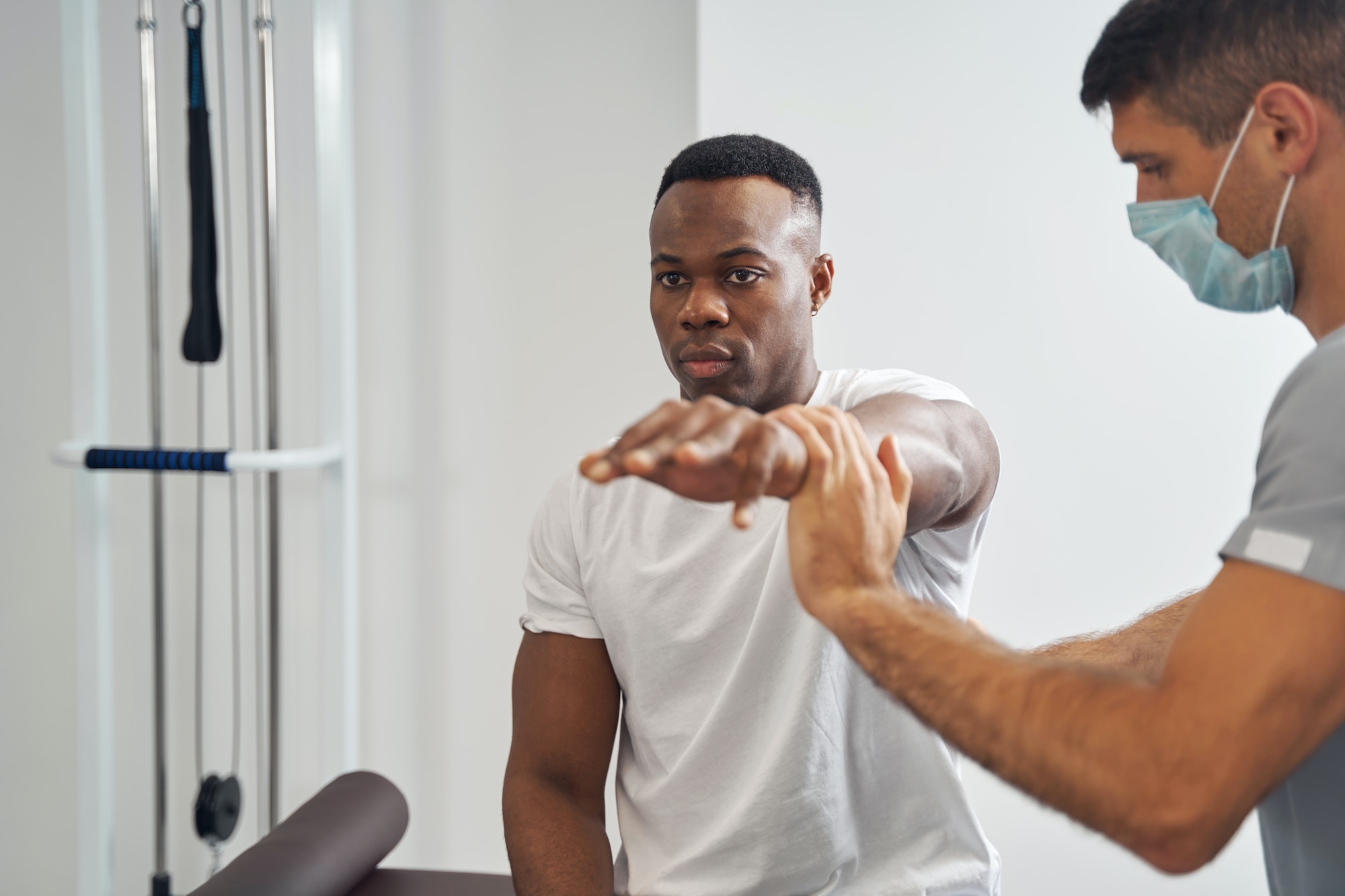 Concentrated physiotherapist assessing muscle strength of young man