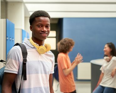 Portrait of an African American student looking at the camera in the school hallway.