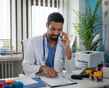 Young male doctor managing phone calls in his office